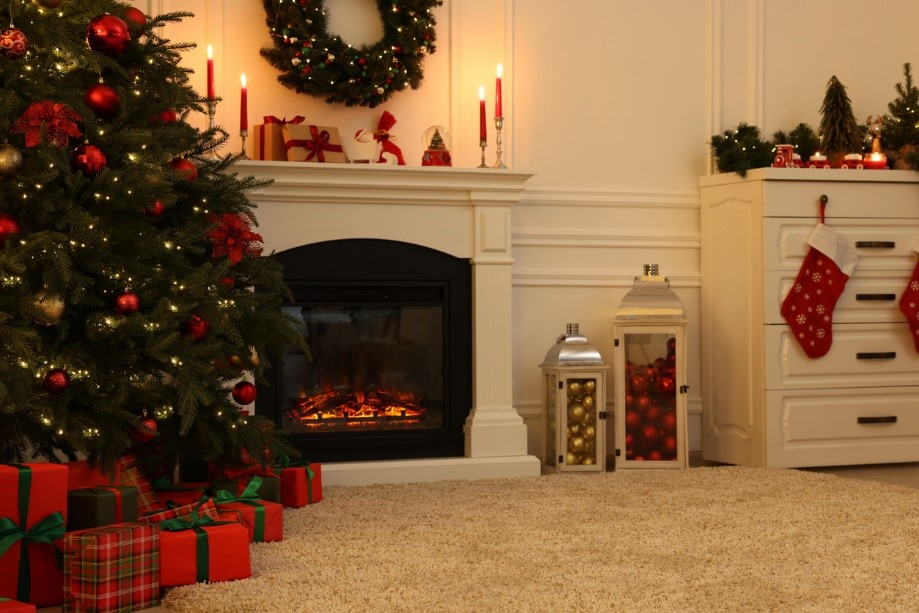 A christmas tree with presents under a fireplace Description automatically generated